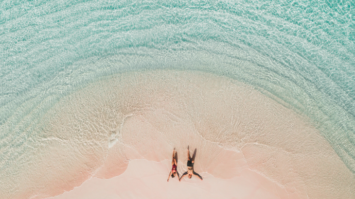 Deux amoureux couchés sur une plage de sable blanc bordé d'eau turquoise