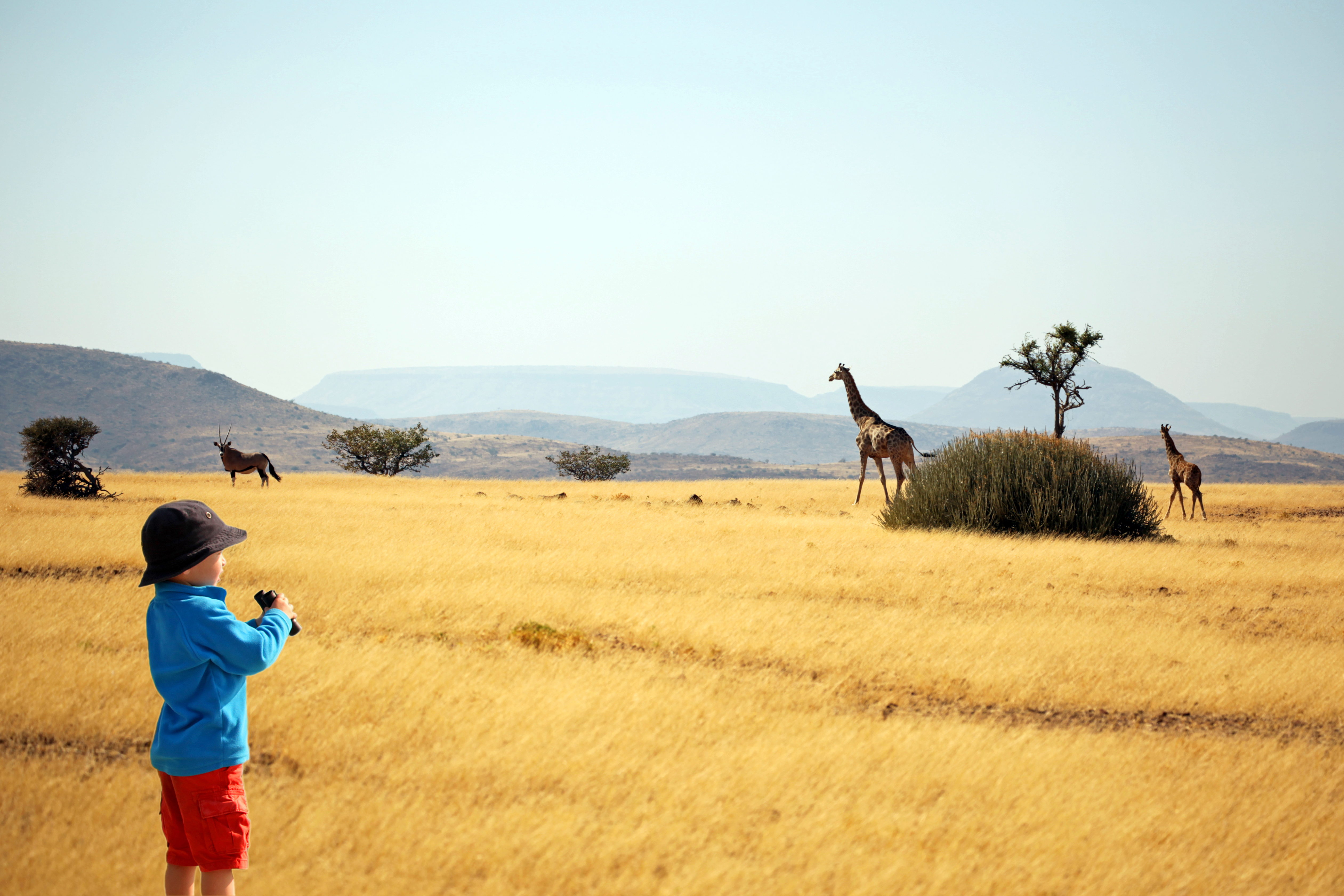 Child with binoculars watching animals on safari in Africa