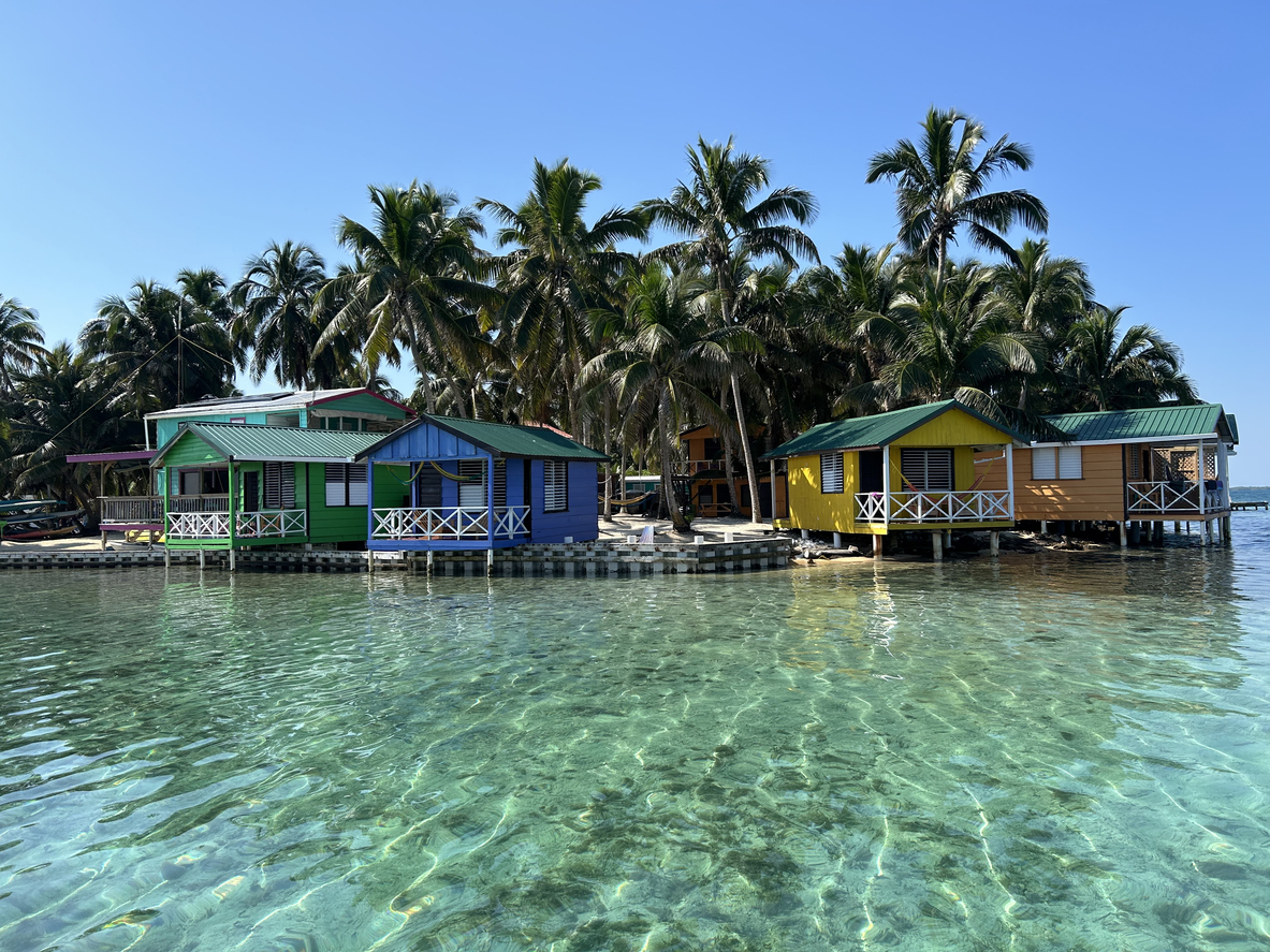 Bungalows sur l'eau et palmiers à Tobacco Caye, Belize, Amérique centrale